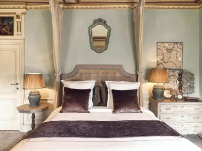a bedroom with a bed with two lamps and a mirror at Kasteel van Ordingen in Sint-Truiden