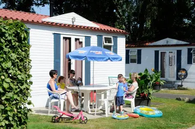 a group of people sitting around a table with an umbrella at Vakantiepark Wilhelm Tell Superieur Chalet in Oudsbergen
