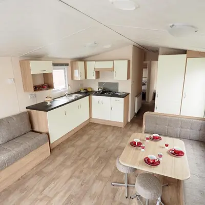 a kitchen and living room with a table and a couch at Vakantiepark Wilhelm Tell Superieur Chalet in Oudsbergen