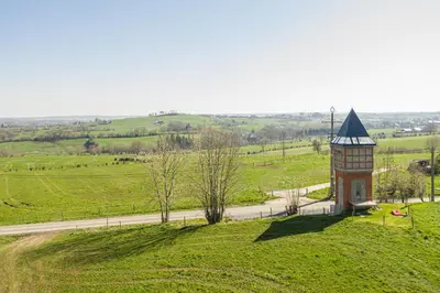 a hill with a clock tower in a field at Logement insolite La tour de Larbuisson in Herve