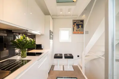 a white kitchen with a staircase and a vase of flowers at Logement insolite La tour de Larbuisson in Herve