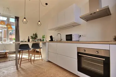 a kitchen with white cabinets and a table and chairs at Tokyo's Place in Liège
