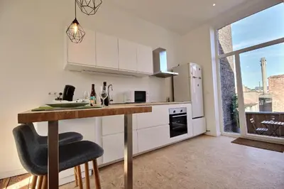 a kitchen with white cabinets and a counter with a table at Tokyo's Place in Liège