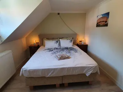 a bedroom with a bed with white sheets and two lamps at Haspengouws Hoeveke in Borgloon