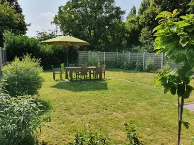 a table and chairs under an umbrella in a yard at Haspengouws Hoeveke in Borgloon