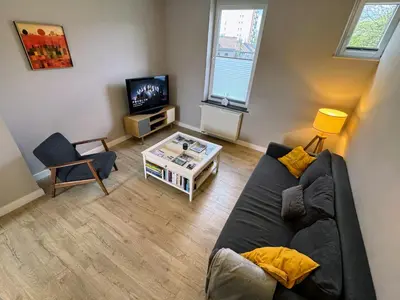 a living room with a couch and a tv at Le Boisseliège in Liège