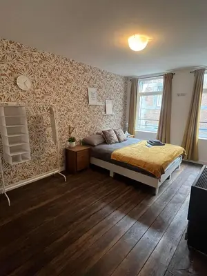 a bedroom with a bed in a room with wooden floors at In The Air cosy room (Cœur Historique de Liège) in Liège