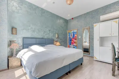 a bedroom with a large bed and a blue wall at Ryad Mogador Liège in Liège