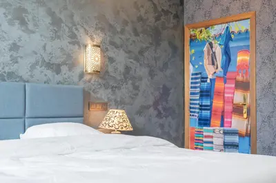 a bedroom with a bed and a lamp and a mirror at Ryad Mogador Liège in Liège