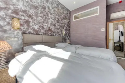 a bedroom with two white beds in it at Ryad Mogador Liège in Liège