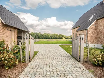 a driveway leading to two buildings with a gate at Peaceful Peer Holiday Home in Peer