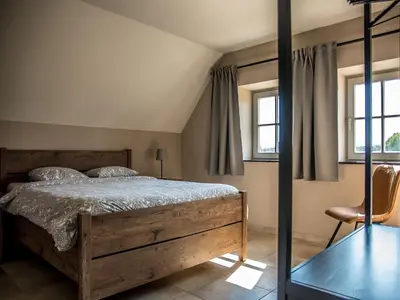 a bedroom with a bed and two windows at Peaceful Peer Holiday Home in Peer