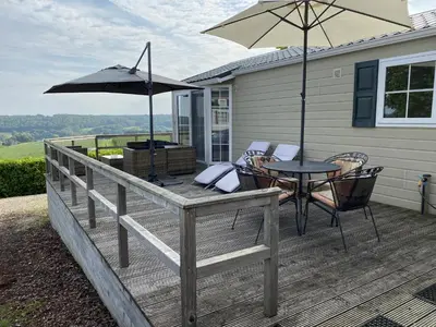 a deck with a table and chairs and an umbrella at Chalet 11 - Bergzicht Teuven in Teuven