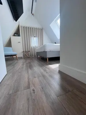 a bedroom with wooden floors and a bed in a attic at B&B Villa Mimosa in Pelt