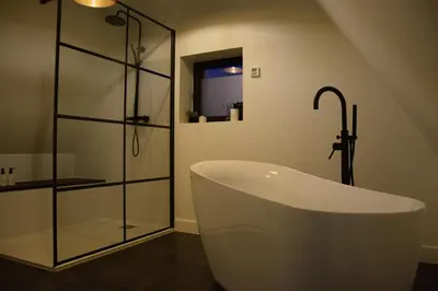 a bathroom with a tub and a glass shower at B&B Villa Mimosa in Pelt