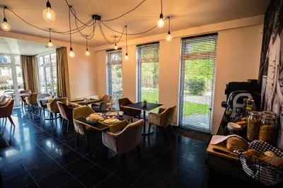 a dining room with tables and chairs and windows at Burgemeesterhuys in Beringen