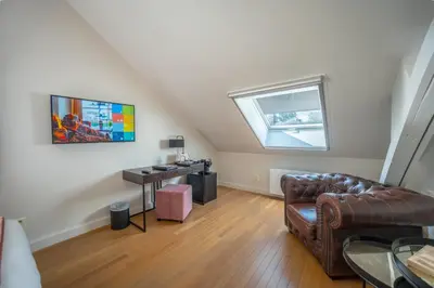 a living room with a leather couch and a window at Burgemeesterhuys in Beringen