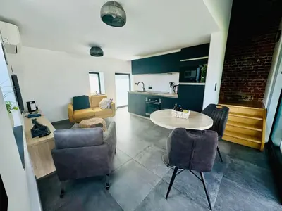 a living room with a table and chairs and a kitchen at Les gîtes de Bouxhmont in Herve