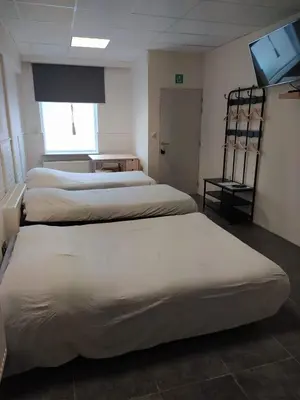 a room with three beds and a flat screen tv at The Place in Lommel