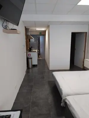 a room with a bed and a hallway with a kitchen at The Place in Lommel