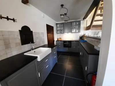 a kitchen with black counters and a white sink at Het Stalhuys in Riemst