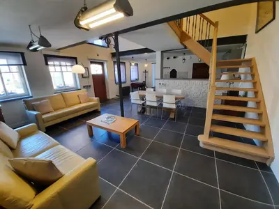 a living room with a couch and a staircase at Het Stalhuys in Riemst