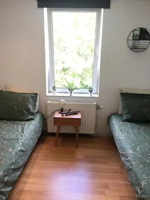 a room with two beds and a table in front of a window at Les charmilles in Chaudfontaine