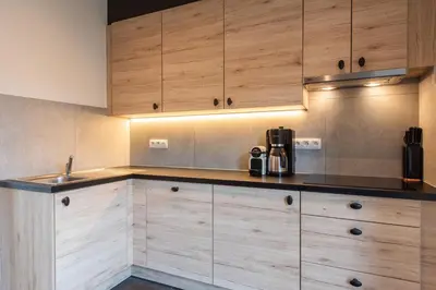 a kitchen with wooden cabinets and a sink at NEW - De sheeper - 10Personen - 5slaapkamers - Sauna - Jacuzzi in Riemst