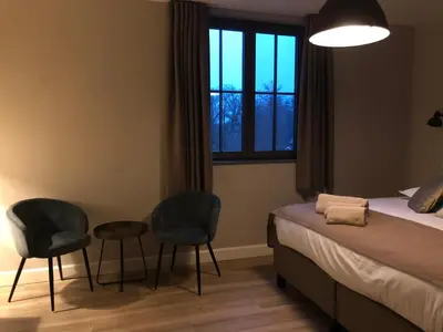 a bedroom with two chairs and a bed and a window at B & B De Romeinse Katzei in Borgloon