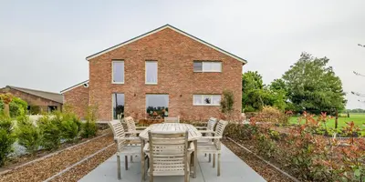 a table and chairs in front of a brick house at Bed en Vrijheid in Peer