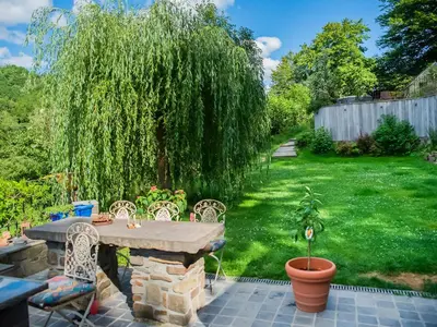 a patio with a table and chairs and a tree at Holiday home with sauna and swimming pool in Verviers