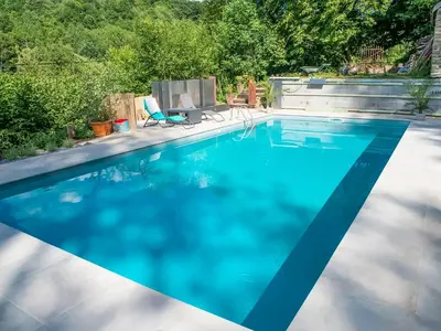 a blue swimming pool with a chair in a yard at Holiday home with sauna and swimming pool in Verviers