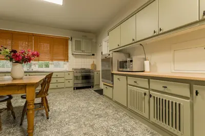 a kitchen with white cabinets and a wooden table at Vakantiewoning De zandberg in Pelt
