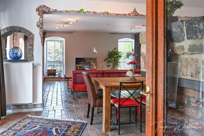 a dining room with a table and a red couch at Landhaus Lontzen in Lontzen