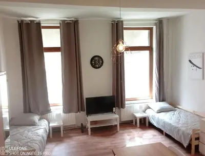 a living room with two beds and a tv at Logement Régence in Liège