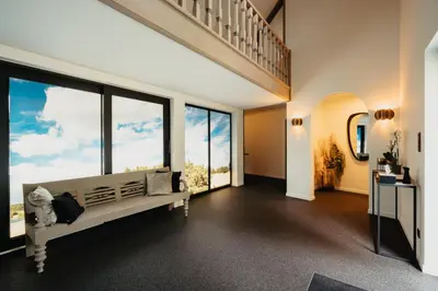 a living room with a large window and a staircase at 't Wilgenhuys in Lommel