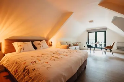 a bedroom with a large bed and a table at 't Wilgenhuys in Lommel