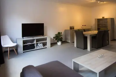 a living room with a flat screen tv and a table at Villa Domus XIX in Tongeren