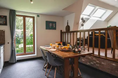 a dining room with a wooden table with chairs at Vakantiewoning & Fietslogies VELO, rustig vlakbij Maastricht in Bilzen