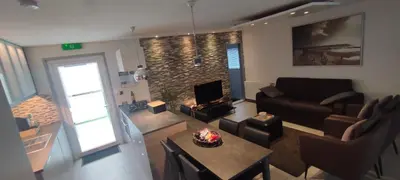 a living room with a couch and a table and a fireplace at Maas Chalet Aldeneik in Maaseik