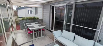a screened in porch with a couch and a table at Maas Chalet Aldeneik in Maaseik