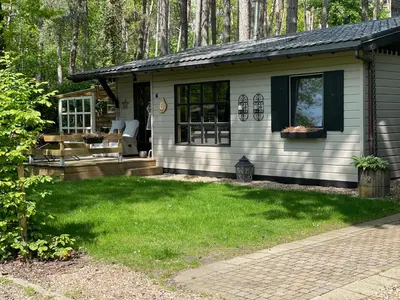 a white house with a patio and a yard at Chalet Sint-Hubertus Deluxe in Zutendaal