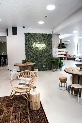 a room with tables and chairs and a green wall at HI Liège Hostel in Liège