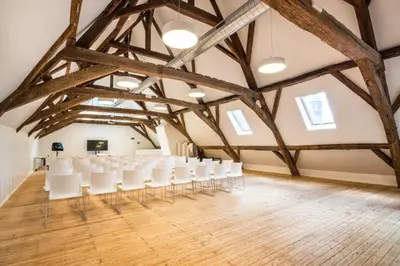 an empty room with white chairs in the attic at HI Liège Hostel in Liège