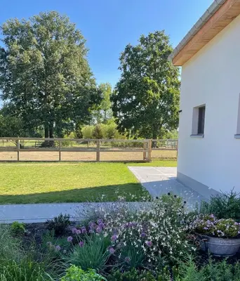 a garden with purple flowers next to a white building at Vakantiewoning Laurijn in Bilzen