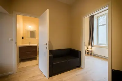 a bathroom with a black chair and a sink at B&B 't Maanhof in Gingelom