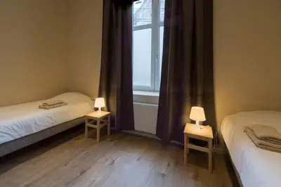 two twin beds in a room with a window at B&B 't Maanhof in Gingelom