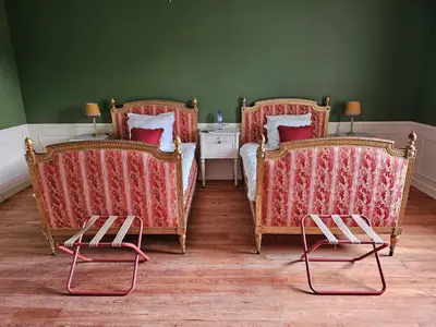 a bedroom with two beds and two chairs at Kasteel Duras in Sint-Truiden