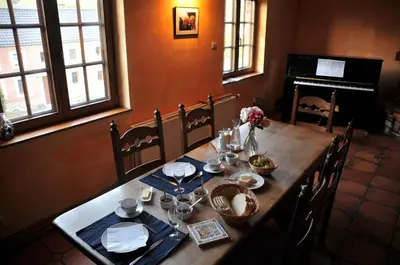 a wooden table with plates and dishes on it with a piano at La Source du Broly in Soumagne