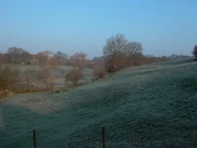 a grassy hill with a fence in a field at La Source du Broly in Soumagne